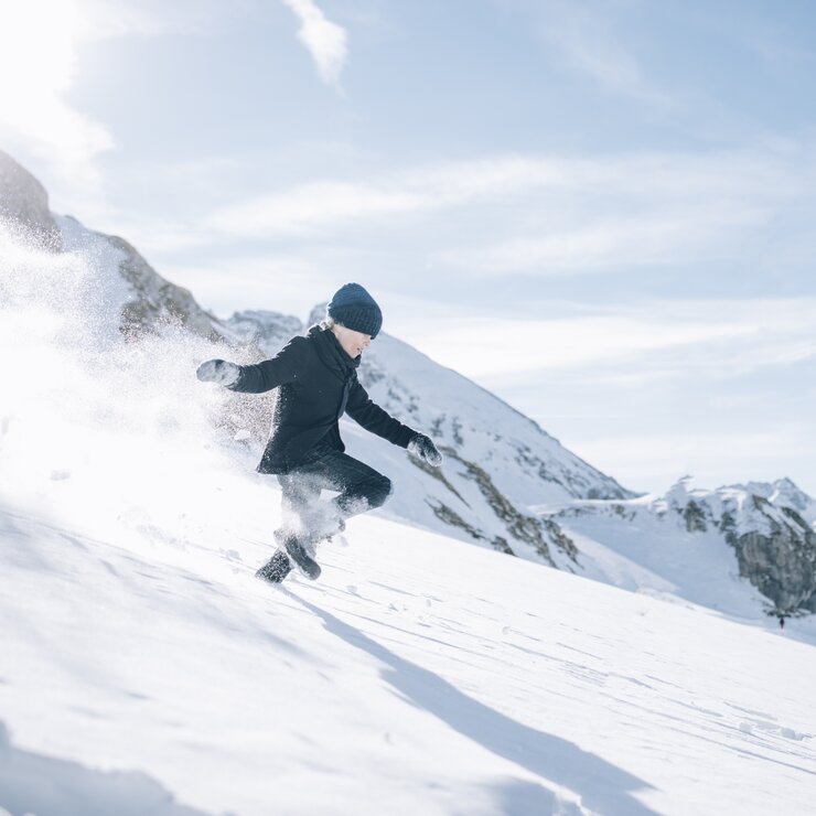 Ein Kind läuft in schwarzer Kleidung durch den Tiefschnee.