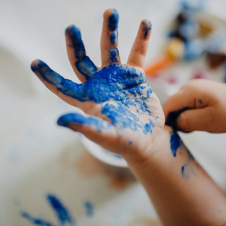 Eine Kinderhand bedeckt mit blauer Farbe, Nahaufnahme der Handfläche.