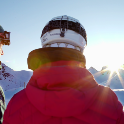 Drei Skifahrer blicken zum Sonnenaufgang in den Bergen.