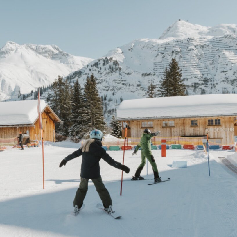 Zwei Kinder üben das Skifahren im Kinderland Oberlech.