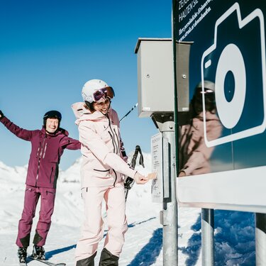 Zwei Skifahrer posieren fröhlich vor dem Photopoint Kriegerhorn.