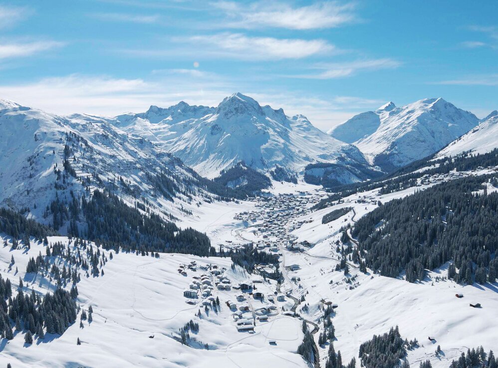 Draufsicht auf eine verschneite Berglandschaft und einem Dorf in der Skiregion Lech Zürs.