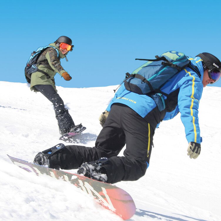 Drei Personen snowboarden über eine schneebedeckte Piste.