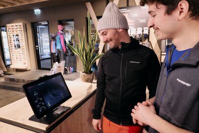 Zwei Männer interagieren mit einem digitalen Display in einem Sportgeschäft.