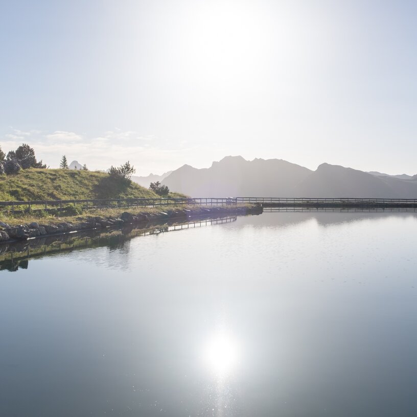 Eine ruhige Seelandschaft mit Lichtreflexionen und Bergblick.
