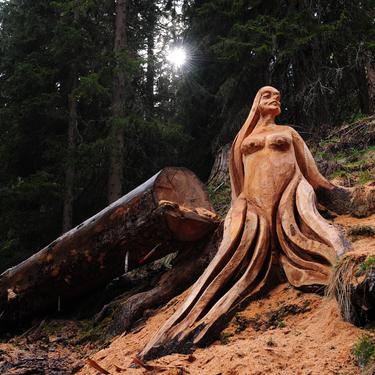 Eine aus einem Baum geschnitzte Skulptur einer Frau im Wald.