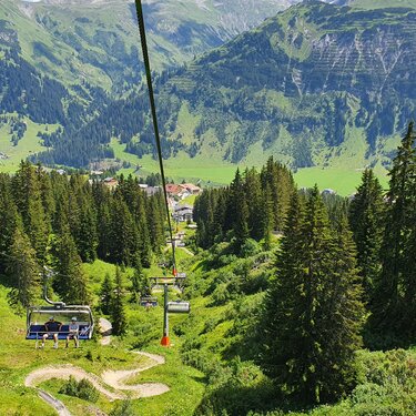 Blick auf eine Seilbahn und grüne Berglandschaft am Familienberg Kriegerhorn.