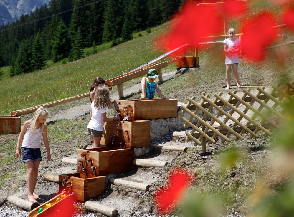 Kinder erkunden ein Wasserspielzeug am Familienberg Kriegerhorn.