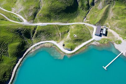 Luftaufnahme vom Zürsersee, der in türkiser Farbe in der Sonne scheint am Naturberg Seekopf.