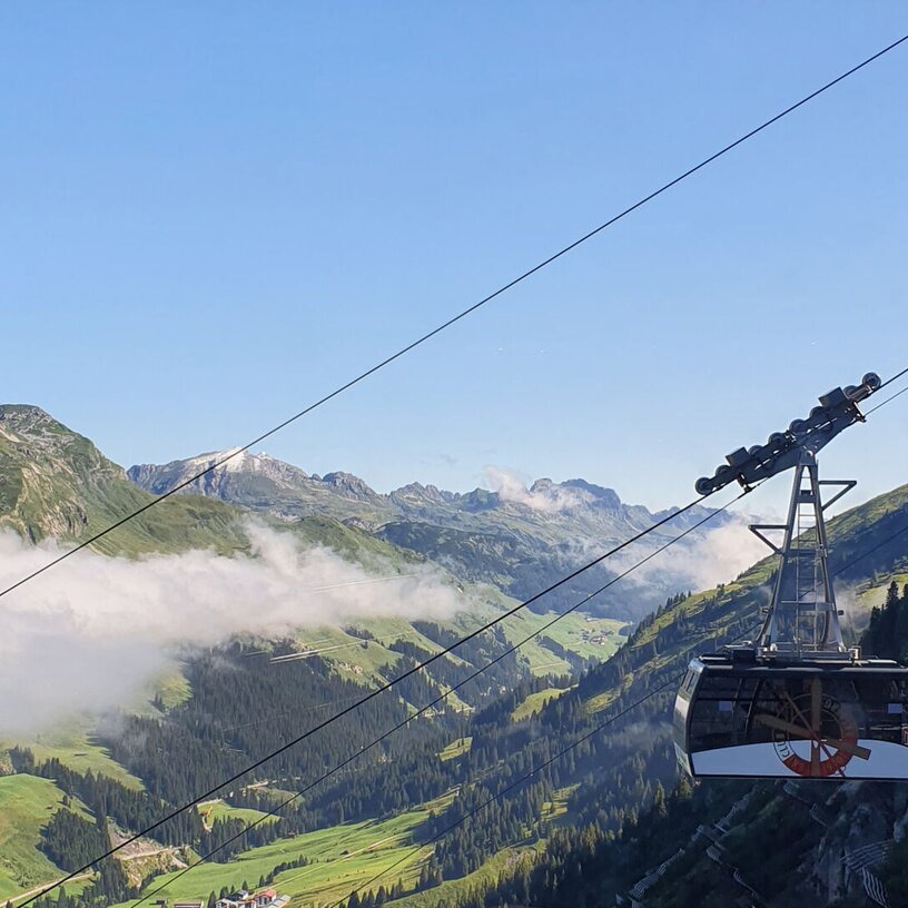 Blick auf eine Seilbahn in den Bergen bei klarem Himmel.