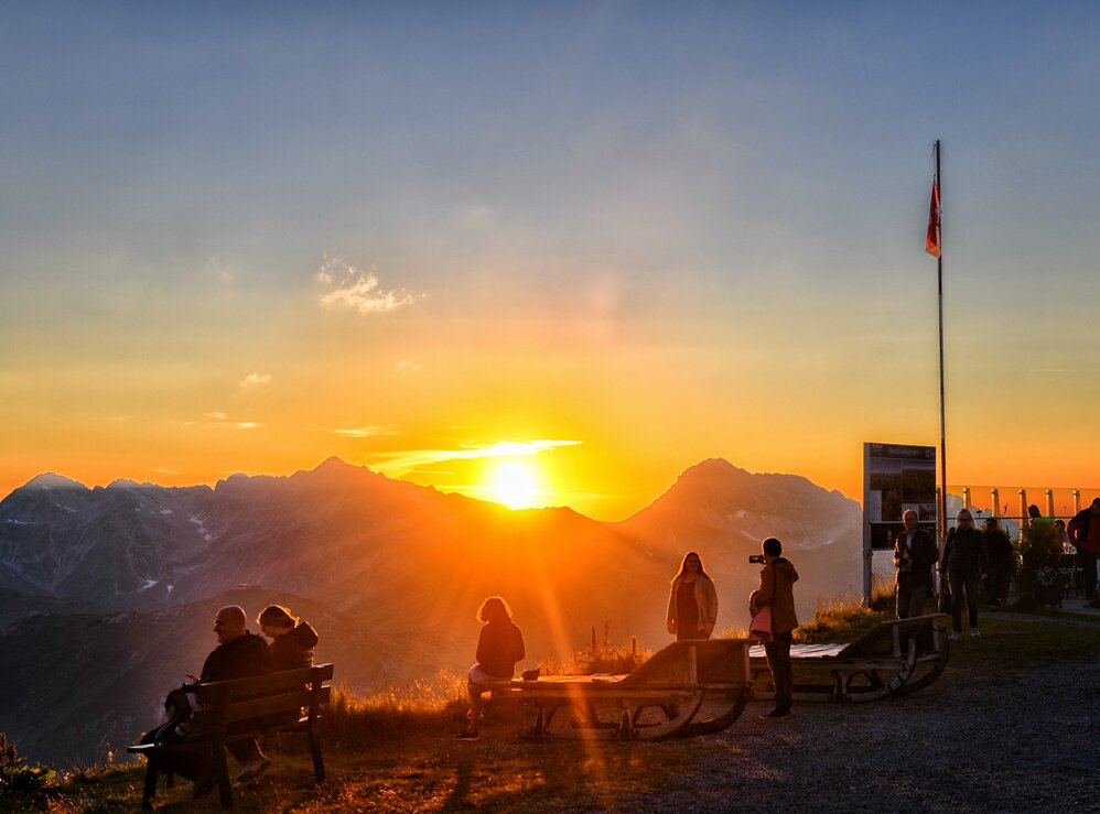 Menschen genießen einen Sonnenuntergang am Panoramaberg Rüfikopf.