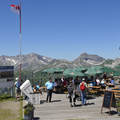 Menschen genießen auf der Terrasse des Panoramarestaurant die Aussicht vom Rüfikopf.