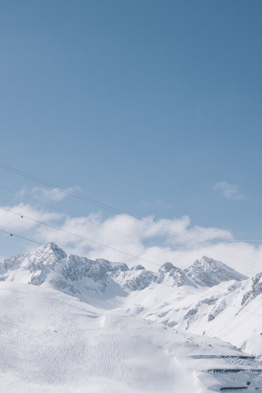 Winterliche Berglandschaft mit Seilbahn vor blauem Himmel.