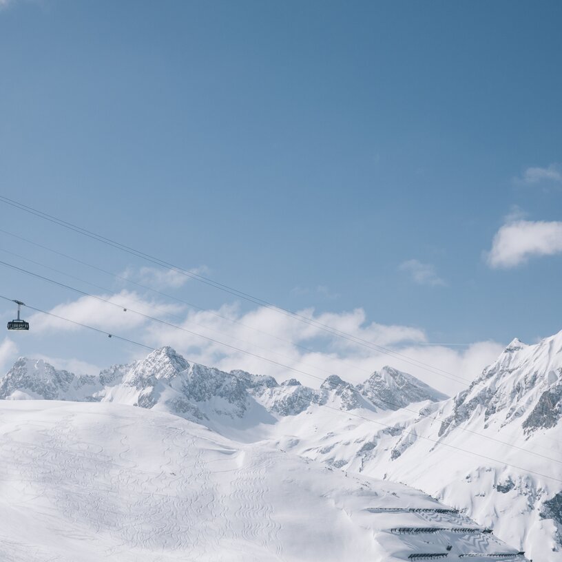 Winterliche Berglandschaft mit Seilbahn vor blauem Himmel.