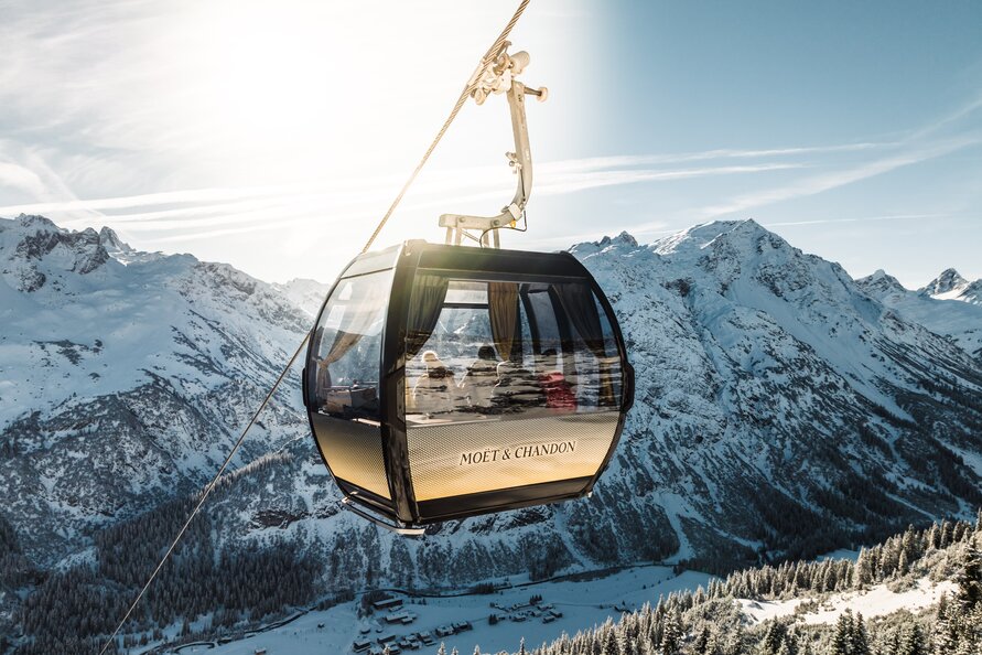 Gondel mit der Aufschrift Moët & Chandon schwebt über schneebedeckten Alpen in Arlberg.