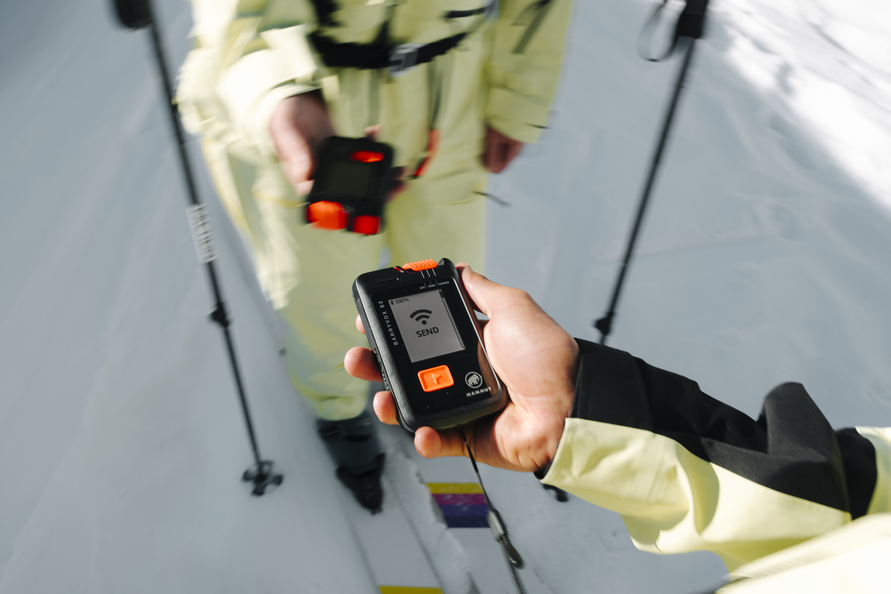 Zwei Personen verwenden LVS-Geräte bei der Mammut Safety Roadshow im Schnee.