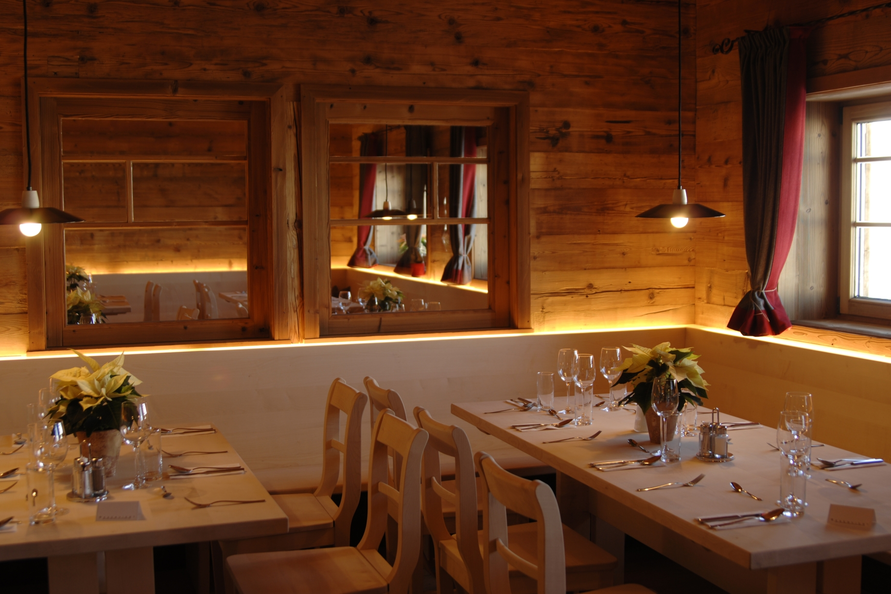 Ein holzverkleideter Restaurantbereich in Balmalp mit gedeckten Tischen und sanfter Beleuchtung.