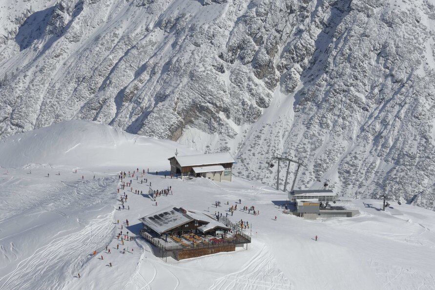 Berglandschaft mit Seekopf Restaurant, Skifahrern und Sessellift.