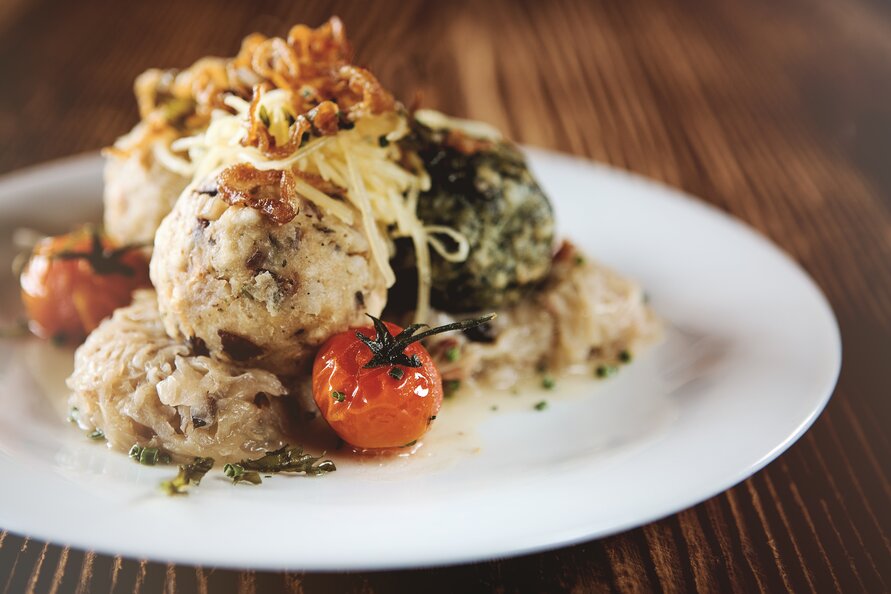 Leckere Knödel mit gebratenen Zwiebeln und Kirschtomaten auf einem weißen Teller angerichtet im Seekopf Restaurant serviert.