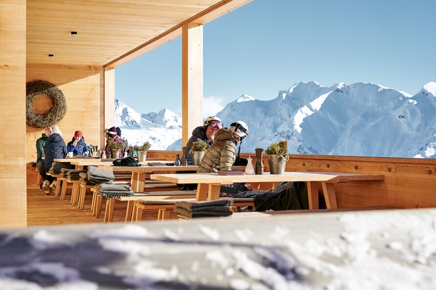 Gäste genießen die Sonne auf der Terrasse des Restaurant Der Wolf.