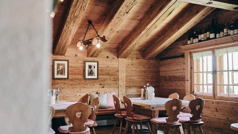 Ein rustikales Esszimmer mit Holztischen und Stühlen im Restaurant Kriegeralpe.