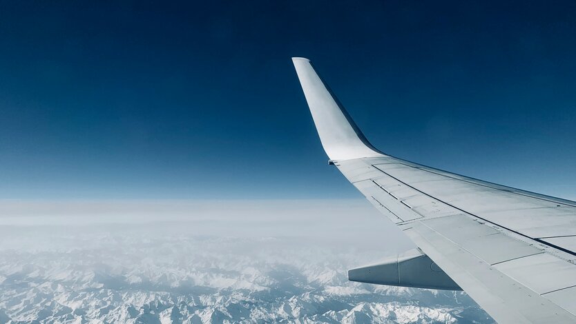 Blick auf schneebedeckte Berge aus einem Flugzeugfenster.