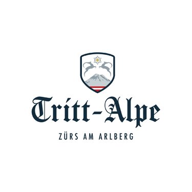 Logo der Tritt-Alpe in Zürs am Arlberg mit Bergmotiv.