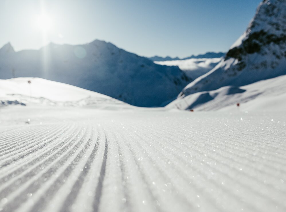 Perfekt präparierte Skipiste in Nahaufnahme im Sonnenschein.