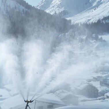 Schneekanone produziert Schnee in einer winterlichen Berglandschaft.