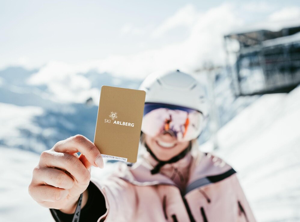 Person auf der Piste zeigt Skipass von Ski Arlberg.