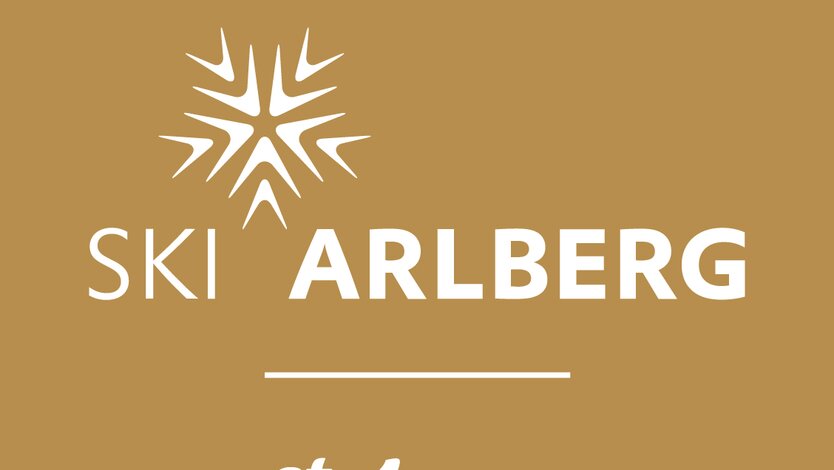 Das Logo von Ski Arlberg in St. Anton auf braunem Hintergrund.