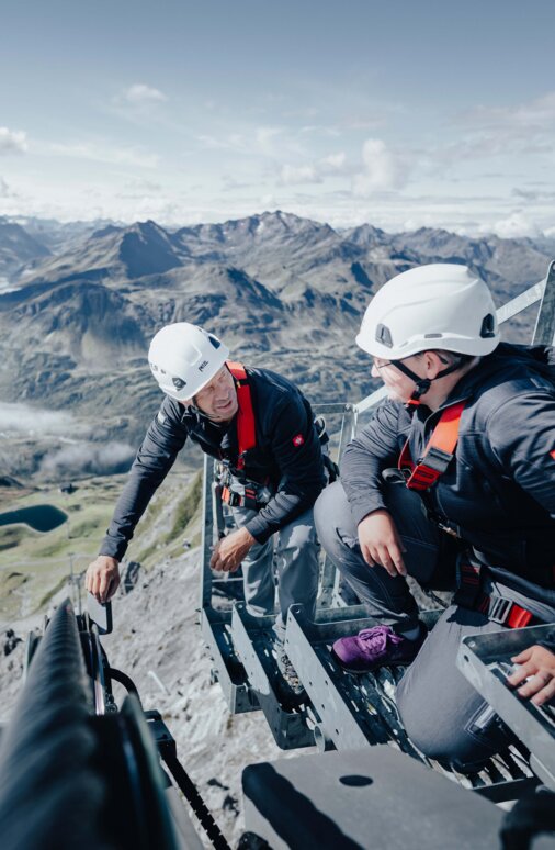 Zwei Männer führen im Sommer eine technische Überprüfung einer Seilbahnanlage in St. Anton durch.