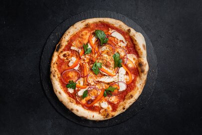 Handgemachte Pizza mit Tomaten, Paprika, Zwiebeln und Petersilie.