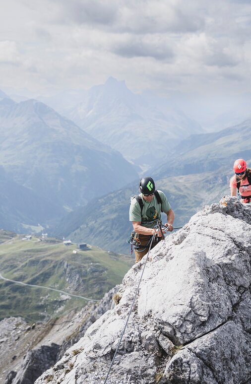 Gruppe von Kletterern auf einem felsigen Grat in den Alpen.