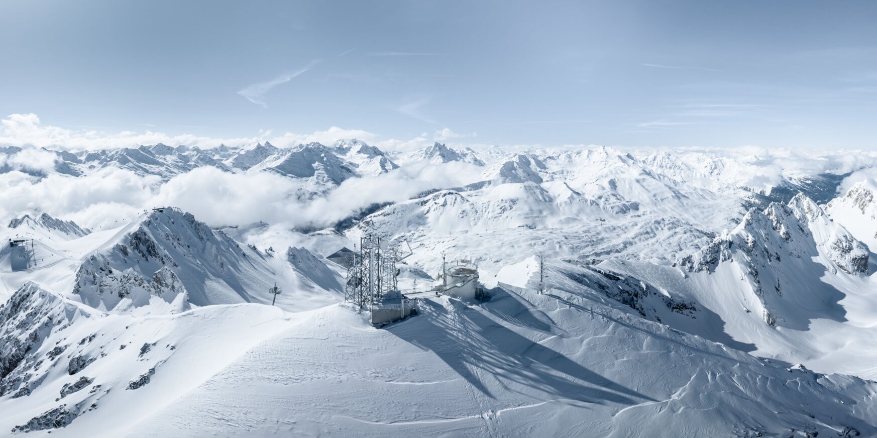 Verschneite Berge unter blauem Himmel mit strahlendem Sonnenschein.