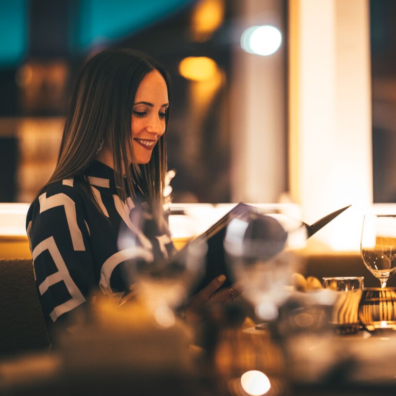 Eine Frau wirft einen Blick in die Speisekarte beim Dinner.