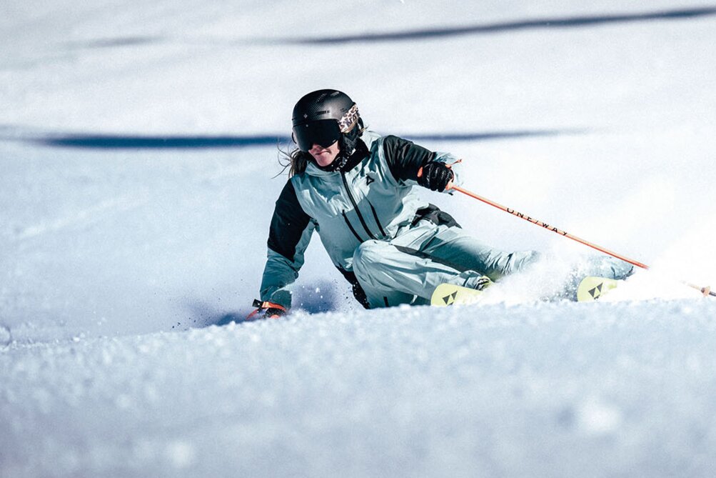 Ein Skifahrer in voller Ausrüstung fährt dynamisch über eine Piste im Skigebiet Ski Arlberg.