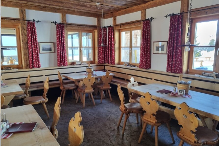 Gaststube der Aufelder Hütte mit Holzmöbeln und karierten Vorhängen.