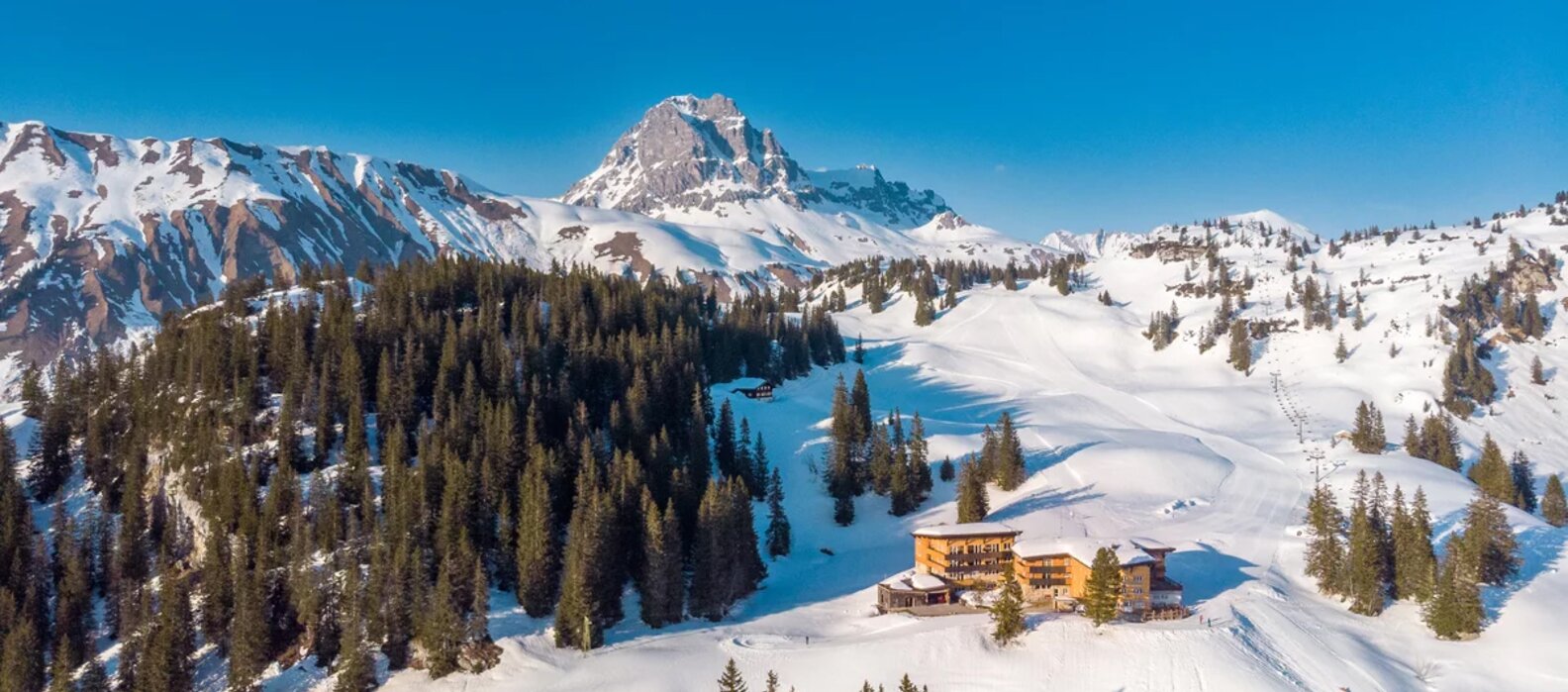 Schneebedeckte Berge mit dem Berghotel Körbersee im Vordergrund.