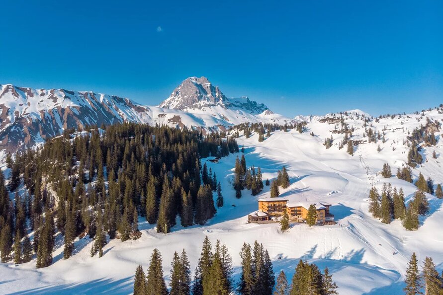 Schneebedeckte Berge mit dem Berghotel Körbersee im Vordergrund.
