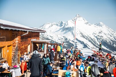 Skifahrer genießen sonnige Terrasse der Punschhütte Wartherhorn.