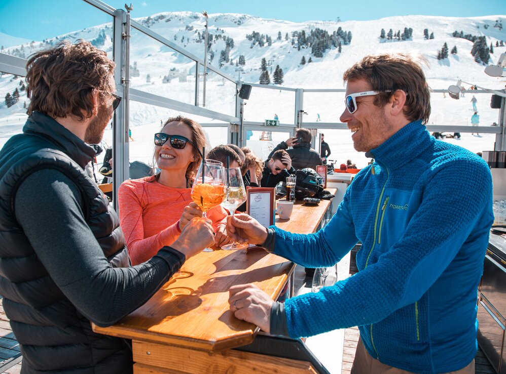 Personen genießen Drinks in der S1 Skilounge mit Bergblick.