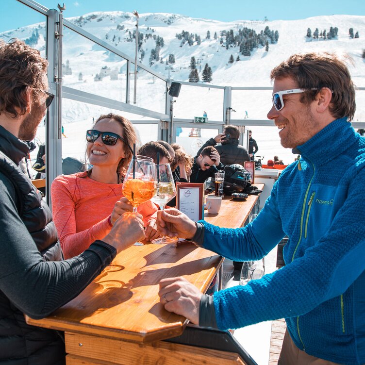 Personen genießen Drinks in der S1 Skilounge mit Bergblick.
