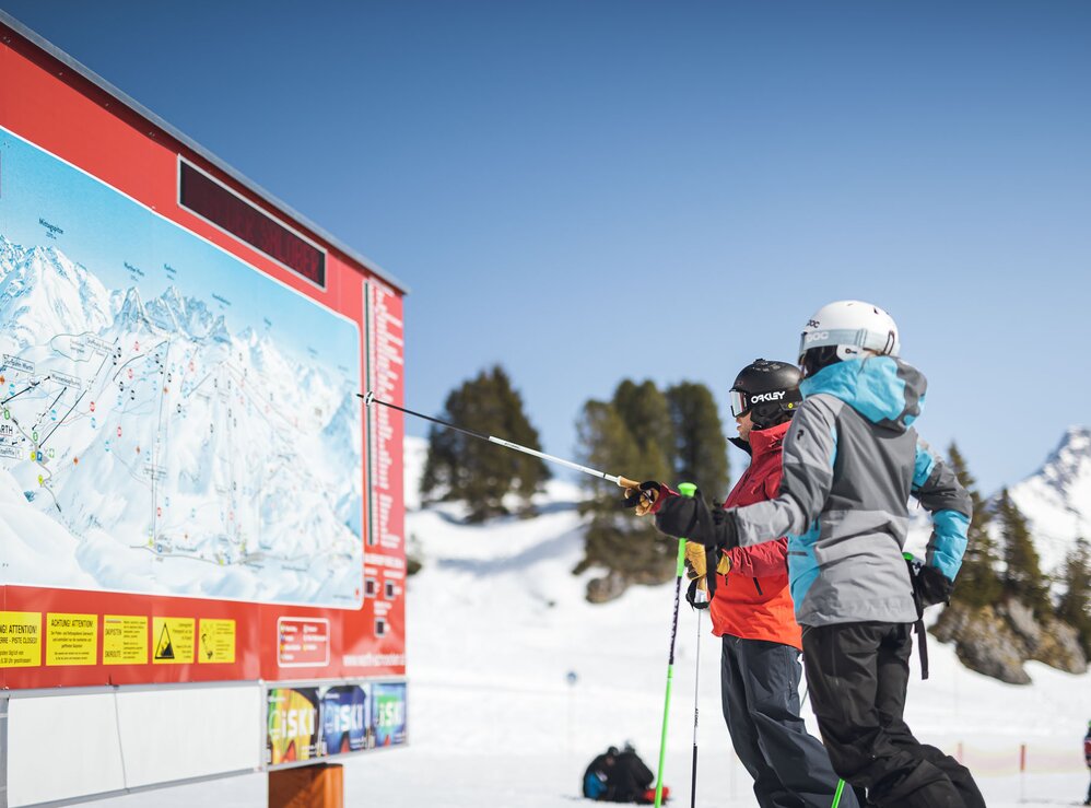 Zwei Skifahrer studieren eine Pistenkarte im Skigebiet Ski Arlberg.
