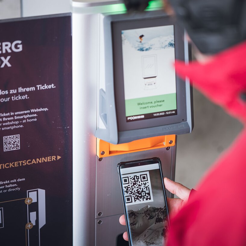 Person scannt QR-Code an einem Ski Arlberg Ticketautomaten.