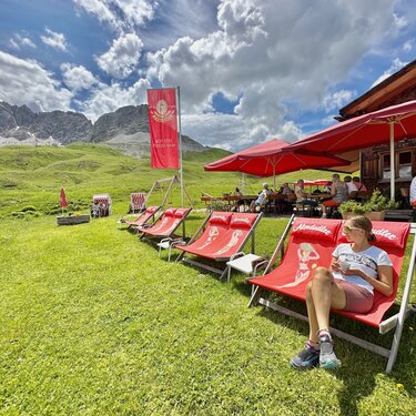 Person entspannt sich in einem Liegestuhl vor einer Hütte in am Arlberg.